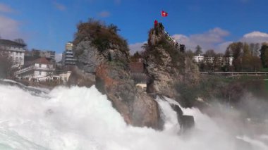 Hızlı fırtınalı soğuk su damlaları düşer ve küçük damlalar Rhine Şelaleleri 'ne İsviçre' deki eski kasabanın arka planına doğru farklı yönlere dağılır. 4k video yavaş çekim UHD