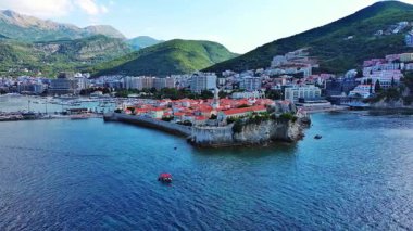 Küçük gemileri ve tekneleri olan deniz turizm limanı antik tarihi Budva adası yakınlarındaki Adriyatik Denizi 'nde romantik bulutlu gökyüzüne karşı. UHD Video gerçek zamanlı 4K