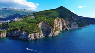 Sığ gök mavisi Adriyatik Denizi 'nin dalgaları üzerinde vahşi yeşil bitki örtüsüyle kayalık bir uçurum. UHD Video gerçek zamanlı 4K