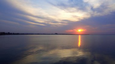Deniz ufkunun arka planında, bulutlu, çok renkli gökyüzü ve parlak akşam günbatımıyla birlikte sakin, mavi, sessiz Karadeniz 'deki büyüleyici yansımanın görüntüsü. HD gerçek zamanlı video