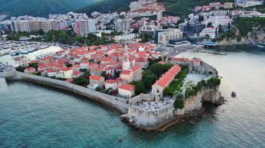 Küçük gemileri ve tekneleri olan deniz turizm limanı antik tarihi Budva adası yakınlarındaki Adriyatik Denizi 'nde romantik bulutlu gökyüzüne karşı. UHD Video gerçek zamanlı 4K