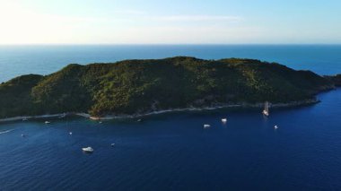 Tarihsel antik turizm adası Aziz Niklas 'ta, açık arkaplan üzerindeki gök mavisi Adriyatik Denizi' nin kayalık kıyılarında bitki örtüsü ile. UHD Video gerçek zamanlı 4K