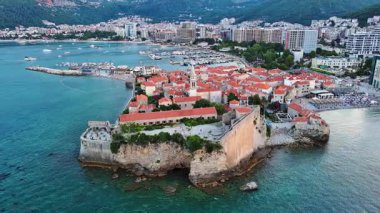 Küçük gemileri ve tekneleri olan deniz turizm limanı antik tarihi Budva adası yakınlarındaki Adriyatik Denizi 'nde romantik bulutlu gökyüzüne karşı. UHD Video gerçek zamanlı 4K