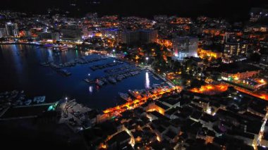 Karadağ dağlarının yamaçlarına ve Adriyatik Denizi yakınlarındaki yıldızlı karanlık gökyüzüne karşı renkli elektrik ışıkları ve plajları olan bir turizm şehri. UHD Video gerçek zamanlı 4K