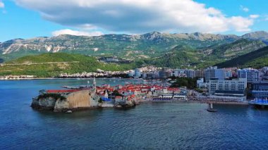 Küçük gemileri ve tekneleri olan deniz turizm limanı antik tarihi Budva adası yakınlarındaki Adriyatik Denizi 'nde romantik bulutlu gökyüzüne karşı. UHD Video gerçek zamanlı 4K