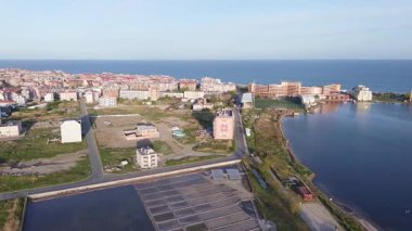 Bulgaristan 'ın kayalık yarımadasında bulunan ve büyük mavi, tuzlu Karadeniz tarafından turlanan küçük ve yoğun nüfuslu Pomorie kasabasına kuş bakışı bir bakış. UHD 4K video gerçek zamanlı