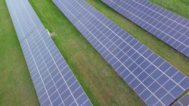 Modern eco-friendly large solar panels to generate energy from suns rays are installed in endless meadows with green grass, under a clear blue sky with bright warm spring sun. UHD 4K video realtime