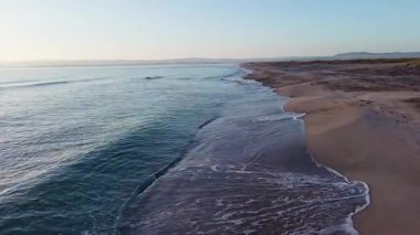 Sakin mavi uçsuz bucaksız Karadeniz, ışığı yansıtan soğuk su ve yakındaki kumlu boş kumsal, bulutlu renkli gökyüzüne karşı beyaz bulutlar ve parlak şafak güneşi. UHD 4K video gerçek zamanlı
