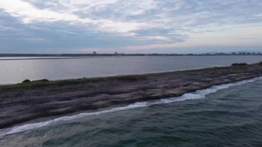 Kuşlar, kumsalın kuru kumla kaplı dar ve sessiz sahil manzarası ve Karadeniz 'in turkuaz körfezi ve akşam güneşinde açık mavi gökyüzünün altında küçük göl taşlarıyla yıkanmış taşlar. UHD 4K video gerçek zamanlı