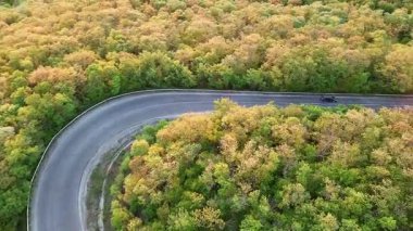 Hızlı modern araba ve kamyonlarla dolambaçlı yeni bir dağ yolu, ufuktaki yeşil yaprak döken ormanlarla Balkan Dağları arasındaki uzaklığa çıkıyor. UHD 4K video gerçek zamanlı