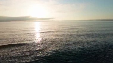 Boundless calm Black Sea with cool water reflecting light extends beyond the horizon, under colored sky with white volatile clouds and a bright dawn warm spring sun. UHD 4K video realtime