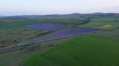 Modern eco-friendly large solar panels to generate energy from suns rays are installed in endless meadows with green grass, under a clear blue sky with bright warm spring sun. UHD 4K video realtime
