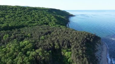 Yaz tatilleri için otelleri ve hanları olan küçük bir tatil köyü yeşil bitki örtüsü ile kayalık ve keskin uçurumlar üzerinde, açık mavi gökyüzüne karşı vahşi Karadeniz üzerinde. UHD 4K video gerçek zamanlı