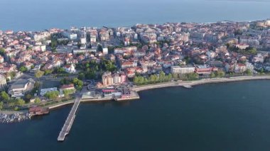 Bulgaristan 'ın kayalık yarımadasında bulunan ve büyük mavi, tuzlu Karadeniz tarafından turlanan küçük ve yoğun nüfuslu Pomorie kasabasına kuş bakışı bir bakış. UHD 4K video gerçek zamanlı