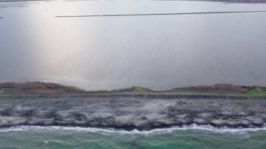 Kuşlar, kumsalın kuru kumla kaplı dar ve sessiz sahil manzarası ve Karadeniz 'in turkuaz körfezi ve akşam güneşinde açık mavi gökyüzünün altında küçük göl taşlarıyla yıkanmış taşlar. UHD 4K video gerçek zamanlı