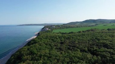 Yaz tatilleri için otelleri ve hanları olan küçük bir tatil köyü yeşil bitki örtüsü ile kayalık ve keskin uçurumlar üzerinde, açık mavi gökyüzüne karşı vahşi Karadeniz üzerinde. UHD 4K video gerçek zamanlı