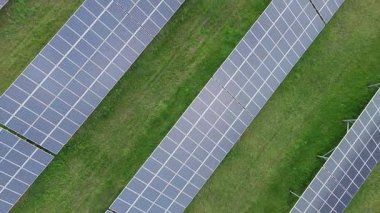 Modern eco-friendly large solar panels to generate energy from suns rays are installed in endless meadows with green grass, under a clear blue sky with bright warm spring sun. UHD 4K video realtime