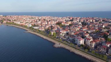 Bulgaristan 'ın kayalık yarımadasında bulunan ve büyük mavi, tuzlu Karadeniz tarafından turlanan küçük ve yoğun nüfuslu Pomorie kasabasına kuş bakışı bir bakış. UHD 4K video gerçek zamanlı