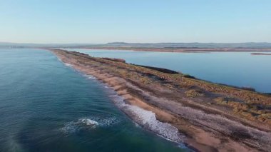 Kuşlar, kumsalın kuru kumla kaplı dar ve sessiz sahil manzarası ve Karadeniz 'in turkuaz körfezi ve akşam güneşinde açık mavi gökyüzünün altında küçük göl taşlarıyla yıkanmış taşlar. UHD 4K video gerçek zamanlı