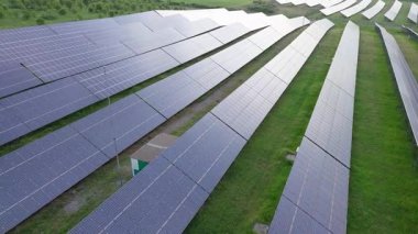 Modern eco-friendly large solar panels to generate energy from suns rays are installed in endless meadows with green grass, under a clear blue sky with bright warm spring sun. UHD 4K video realtime