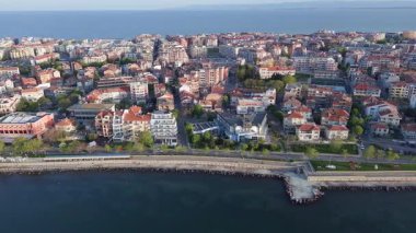 Bulgaristan 'ın kayalık yarımadasında bulunan ve büyük mavi, tuzlu Karadeniz tarafından turlanan küçük ve yoğun nüfuslu Pomorie kasabasına kuş bakışı bir bakış. UHD 4K video gerçek zamanlı