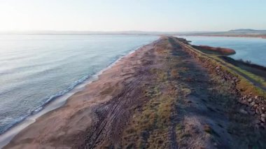 Kuşlar, kumsalın kuru kumla kaplı dar ve sessiz sahil manzarası ve Karadeniz 'in turkuaz körfezi ve akşam güneşinde açık mavi gökyüzünün altında küçük göl taşlarıyla yıkanmış taşlar. UHD 4K video gerçek zamanlı