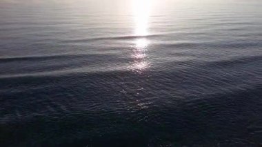 Boundless calm Black Sea with cool water reflecting light extends beyond the horizon, under colored sky with white volatile clouds and a bright dawn warm spring sun. UHD 4K video realtime