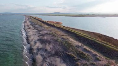 Kuşlar, kumsalın kuru kumla kaplı dar ve sessiz sahil manzarası ve Karadeniz 'in turkuaz körfezi ve akşam güneşinde açık mavi gökyüzünün altında küçük göl taşlarıyla yıkanmış taşlar. UHD 4K video gerçek zamanlı