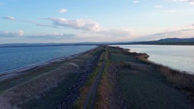 Kuşlar, kumsalın kuru kumla kaplı dar ve sessiz sahil manzarası ve Karadeniz 'in turkuaz körfezi ve akşam güneşinde açık mavi gökyüzünün altında küçük göl taşlarıyla yıkanmış taşlar. UHD 4K video gerçek zamanlı
