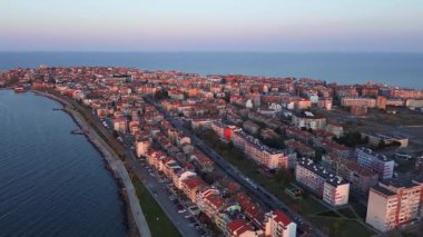 Bulgaristan 'ın kayalık yarımadasında bulunan ve büyük mavi, tuzlu Karadeniz tarafından turlanan küçük ve yoğun nüfuslu Pomorie kasabasına kuş bakışı bir bakış. UHD 4K video gerçek zamanlı