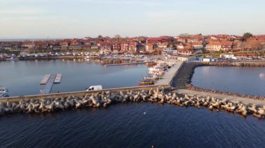Küçük, yeni inşa edilmiş bir tatil köyünün kuş bakışı manzarası - Pomorie yarımadası, büyük, tuzlu, sakin Karadeniz 'de birçok farklı modern tekne ve tekne. UHD 4K video gerçek zamanlı