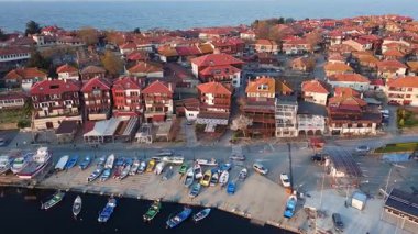 Küçük, yeni inşa edilmiş bir tatil köyünün kuş bakışı manzarası - Pomorie yarımadası, büyük, tuzlu, sakin Karadeniz 'de birçok farklı modern tekne ve tekne. UHD 4K video gerçek zamanlı