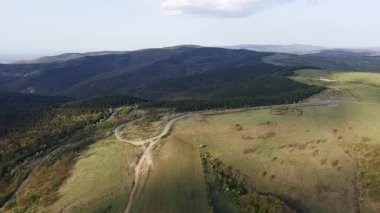 Birds eye view of spring blooming green meadows and wooded hilly slopes of the Balkan Mountains, under the light of a bright cloudy warm day in the country of Bulgaria. UHD 4K video realtime