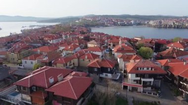 Birds eye view of the modern historic small town of Sozopol with a variety of cozy seaside houses and small sea spring boats, near the calm deep rippled Black Sea. UHD 4K video realtime