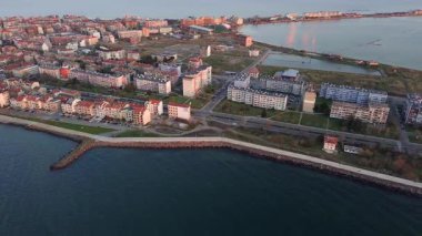 Bulgaristan 'ın kayalık yarımadasında bulunan ve büyük mavi, tuzlu Karadeniz tarafından turlanan küçük ve yoğun nüfuslu Pomorie kasabasına kuş bakışı bir bakış. UHD 4K video gerçek zamanlı