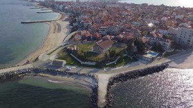 Bulgaristan 'ın kayalık yarımadasında bulunan ve büyük mavi, tuzlu Karadeniz tarafından turlanan küçük ve yoğun nüfuslu Pomorie kasabasına kuş bakışı bir bakış. UHD 4K video gerçek zamanlı