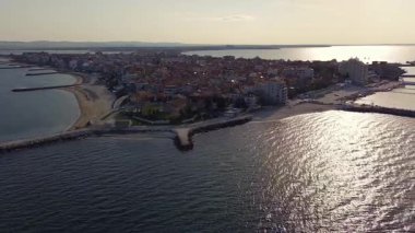 Bulgaristan 'ın kayalık yarımadasında bulunan ve büyük mavi, tuzlu Karadeniz tarafından turlanan küçük ve yoğun nüfuslu Pomorie kasabasına kuş bakışı bir bakış. UHD 4K video gerçek zamanlı