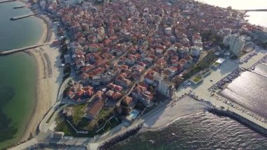 Küçük, yeni inşa edilmiş bir tatil köyünün kuş bakışı manzarası - Pomorie yarımadası, büyük, tuzlu, sakin Karadeniz 'de birçok farklı modern tekne ve tekne. UHD 4K video gerçek zamanlı