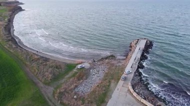 Birds eye view of dense spring green meadows and fields near rocky sandy steep coast, near calm rippled deep Black Sea in light of evening sea sun in warm country of Bulgaria. UHD 4K video realtime