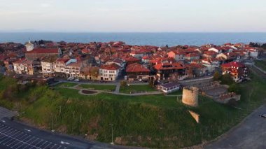 Bulgaristan 'ın Karadeniz kıyısındaki bir yarımadada yürüyen insanlarla dolu yeşil yay parkları ve dar caddelerle kaplı antik deniz kasabası Nesebar' a kuşların bakış açısı. UHD 4K video gerçek zamanlı