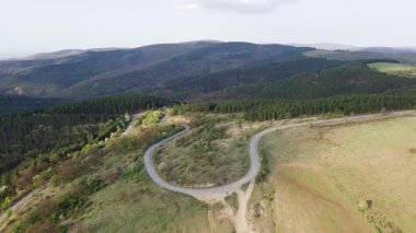Birds eye view of spring blooming green meadows and wooded hilly slopes of the Balkan Mountains, under the light of a bright cloudy warm day in the country of Bulgaria. UHD 4K video realtime