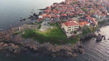 Birds eye view of the modern historic small town of Sozopol with a variety of cozy seaside houses and small sea spring boats, near the calm deep rippled Black Sea. UHD 4K video realtime