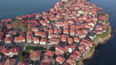 Birds eye view of the modern historic small town of Sozopol with a variety of cozy seaside houses and small sea spring boats, near the calm deep rippled Black Sea. UHD 4K video realtime