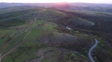 Birds eye view of spring blooming green meadows and wooded hilly slopes of the Balkan Mountains, under the light of a bright cloudy warm day in the country of Bulgaria. UHD 4K video realtime