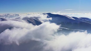 Alışılmadık Carpathian dağ vadisi ladin ormanlarıyla kaplı beyaz kabarık bulutlarla aydınlık kış günbatımında, hava UHD 4K video
