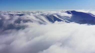 Alışılmadık Carpathian dağ vadisi ladin ormanlarıyla kaplı beyaz kabarık bulutlarla aydınlık kış günbatımında, hava UHD 4K video