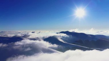 Olağanüstü ve tüylü bir bulut vadisi ve parlak turuncu bir gün batımı, hava UHD 4K videosu.