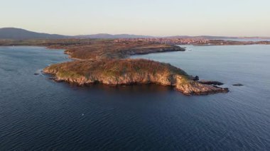 Bulgaristan 'ın açık mavi gökyüzü altında, sessiz turkuaz şeffaf Karadeniz ile çevrili, yabani çimenler ve otellerle kaplı kayalık kumlu dar sahillerin yükseklik ve yanından manzaraya bak. UHD 4K video gerçek zamanlı