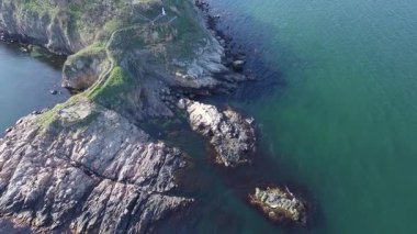 Bulgaristan 'ın parlak güneşli akşam günbatımına karşı sakin, mavi yansıtıcı Karadeniz ve eski karanlık kayalık taşlarla kaplı deniz manzarası. UHD 4K video gerçek zamanlı