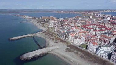 Bulgaristan 'ın kayalık yarımadasında bulunan ve büyük mavi, tuzlu Karadeniz tarafından turlanan küçük ve yoğun nüfuslu Pomorie kasabasına kuş bakışı bir bakış. UHD 4K video gerçek zamanlı